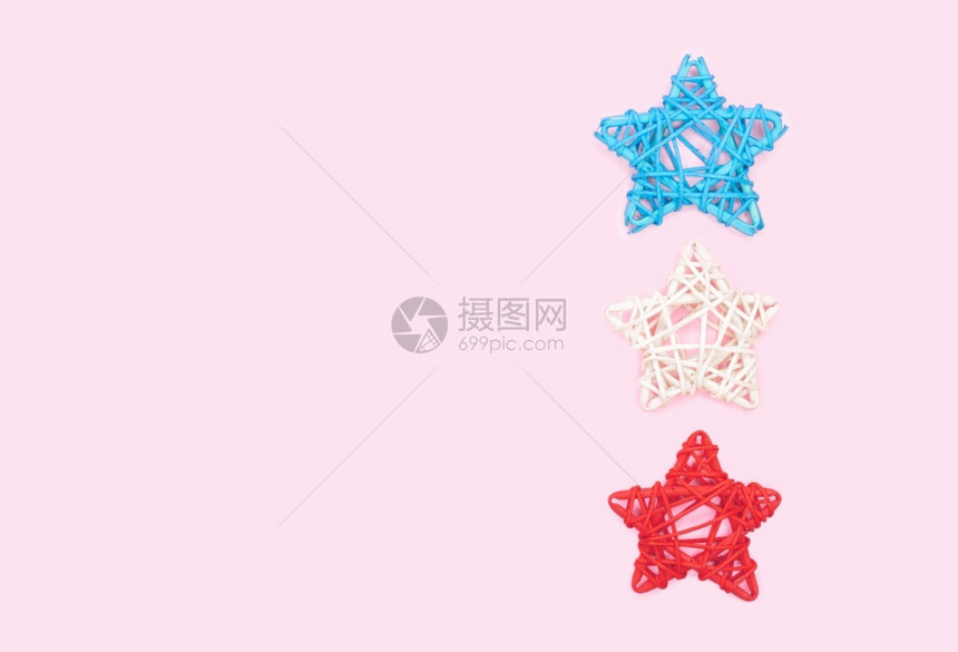 星迷人的木制粉红色背景上用藤条制成的蓝色白和红柳条星的平面装饰粉红色背景上用藤条制成的柳星装饰图片