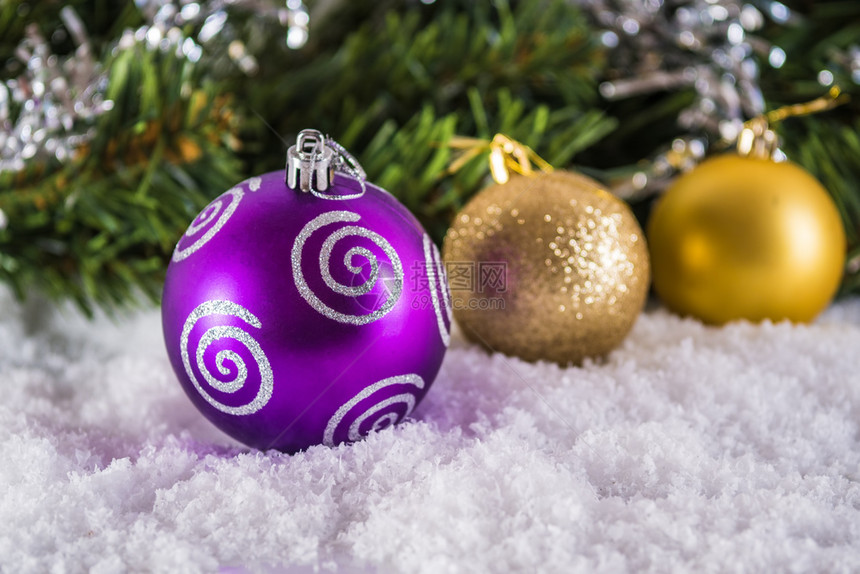 在圣诞树枝模糊不清的背景下雪上圣诞球聚焦在前面的球上领域前夕圆形的图片