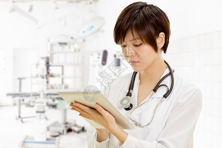 护士使用平板电脑进行外科手术的亚裔女美国医生专业的成人图片