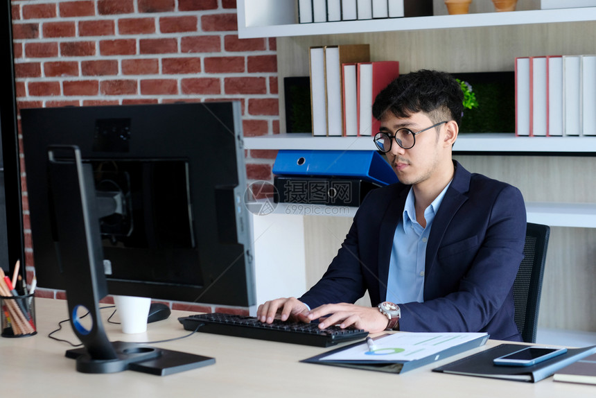 人们亚洲年轻上班族与电脑斗争沮丧的亚洲商人在办公室工作时看着电脑商务人士与技术斗争男成人图片
