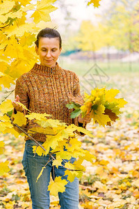 一个笑着的成年天主教女人秋在公园里采黄色的树叶瓜拉纳皮女成人图片