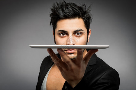 屏幕手指肖像一个人用平板电脑一手在灰色背景的面部前将脸举着平板电脑图片