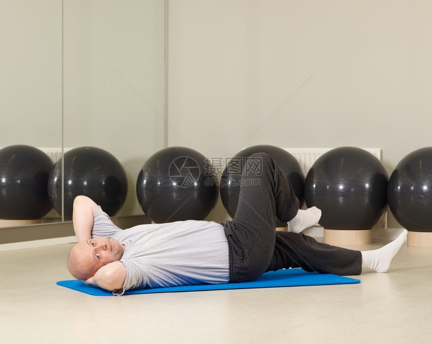 复制成熟的男子照顾自己健康在身房锻炼和伸展体操运动服图片