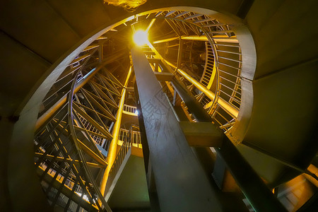 脚步黄色的温暖夜间记录从地下平台通往大楼外部的明亮螺旋楼梯由地下平台到大楼外面的灯光螺旋楼梯背景图片