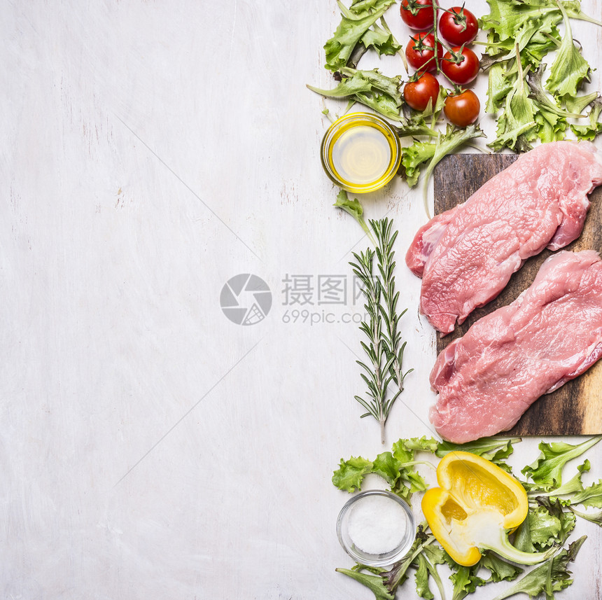 两块猪肉牛排蔬菜在有香料和草药边境的切菜板上木制生锈背景纸质文字的地方最佳调味料劈图片