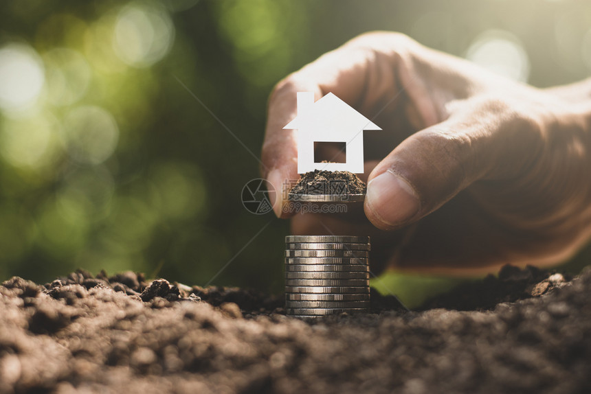 硬币被埋在地上男人的手拿起硬币把小白房子堆叠在一起地面银行业美元图片