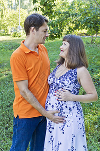 落下棕色的沙腾一对夫妇在绿草上等待着橙色的婴儿图片