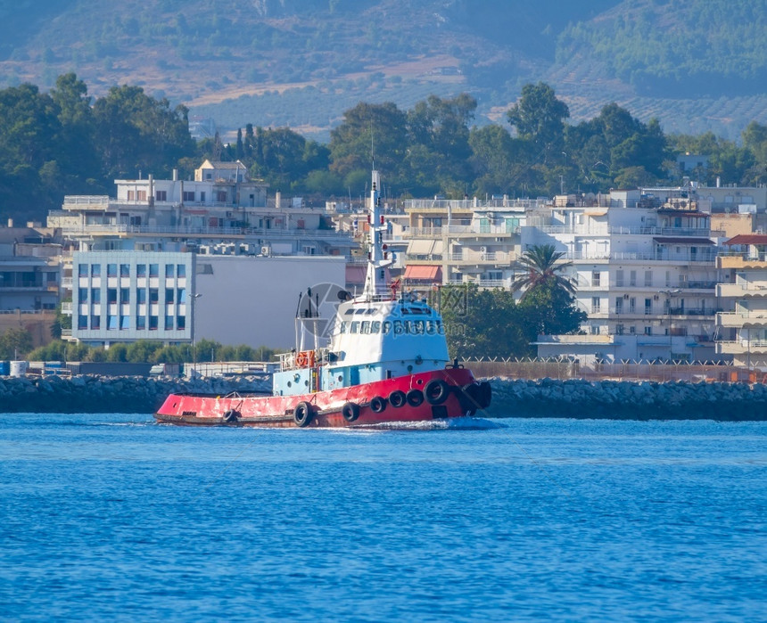 山顶峰航运在科林斯拖船湾的一个小镇红拖船和桑尼夏日海岸与城镇的背景下在科林斯拖船湾的阳光夏日图片