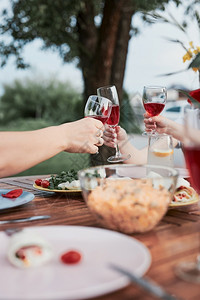派对超过乐趣家人在夏季户外晚宴期间在家庭花园做吐司手举着红酒杯和盘子图片