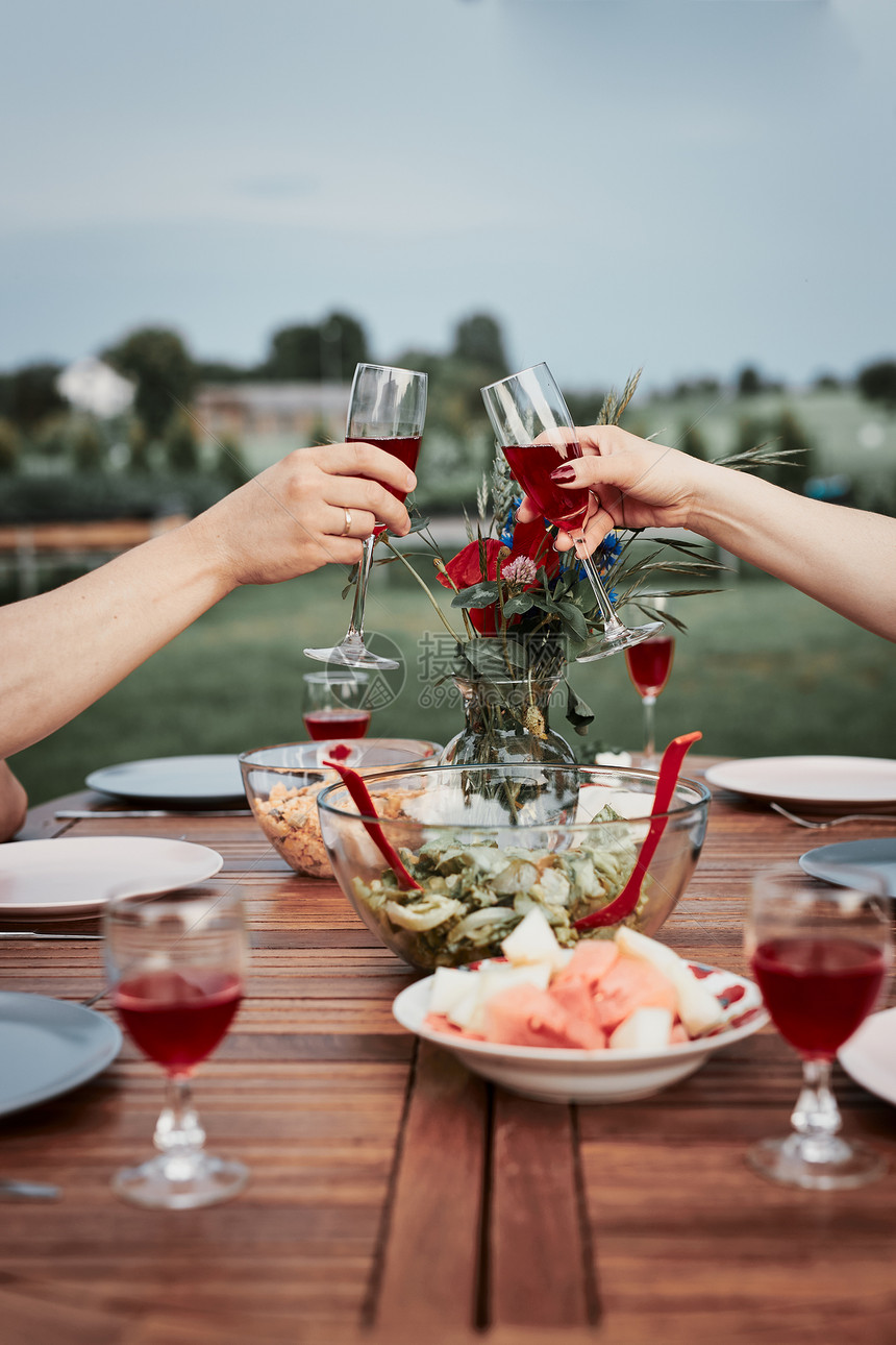 在夏季户外晚宴期间在家庭花园里做烤面包的情侣手拿着红酒杯和以及盘子派对女士保持图片