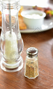 木制桌上的盐和胡椒搅拌机玻璃绿色厨房图片