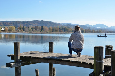 在木制码头对瑞士湖的女孩自由放松孤独图片