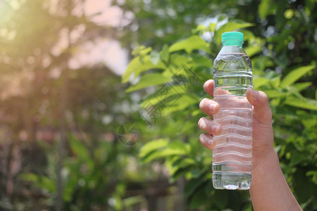 阳光男生瓶子人的手在花园里拿着一瓶饮用水并给你复制空间笑声图片