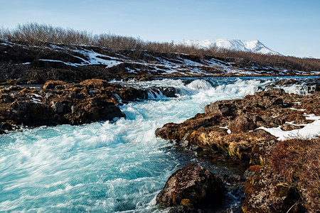 雪在阳光明媚的一天冰岛Midfos瀑布冰岛河Midfos瀑布颜色结石图片
