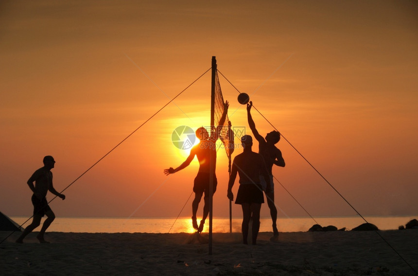 夕阳下海滩打排球的朋友们图片