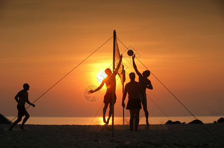 夕阳下海滩打排球的朋友们图片