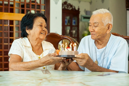 蜡烛亚洲高龄夫妇在客厅里拿着蛋糕笑男人一种图片