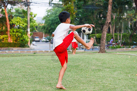 行动东盟白色的在花园踢足球泰国男孩图片