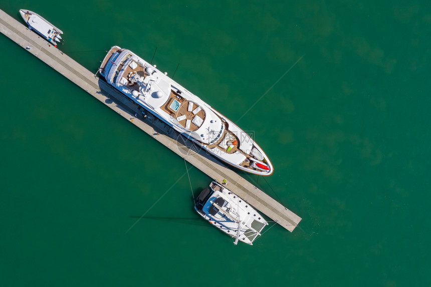 水白色的无人驾驶飞机从泰国普吉岛绿海上空的游艇和快停泊运输图片