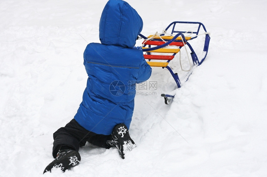 冬天在户外散步小孩坐在雪中腿上玩着多彩的雪橇步行五缤纷季节图片