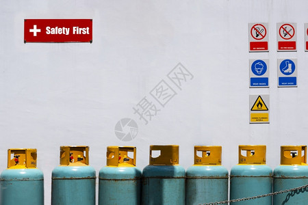 气体活力危险在白色水泥墙背景上贴有安全第一标签和各种警告志的气罐瓶箱图片