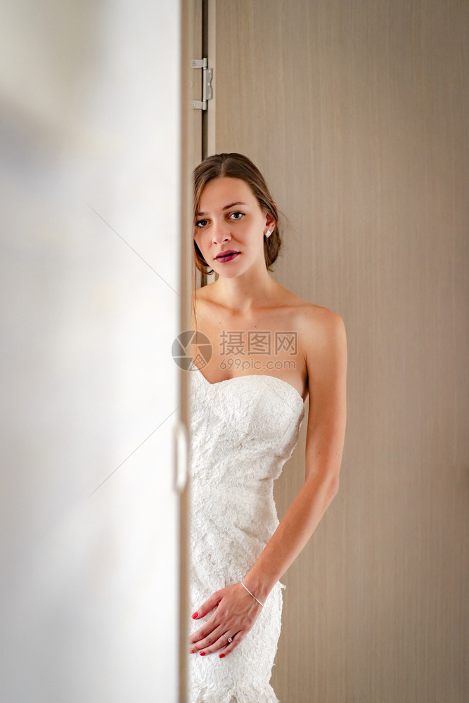 亲热人们身穿白色婚纱站在门口看着摄影机的年轻美女肖像穿着白礼服发型图片
