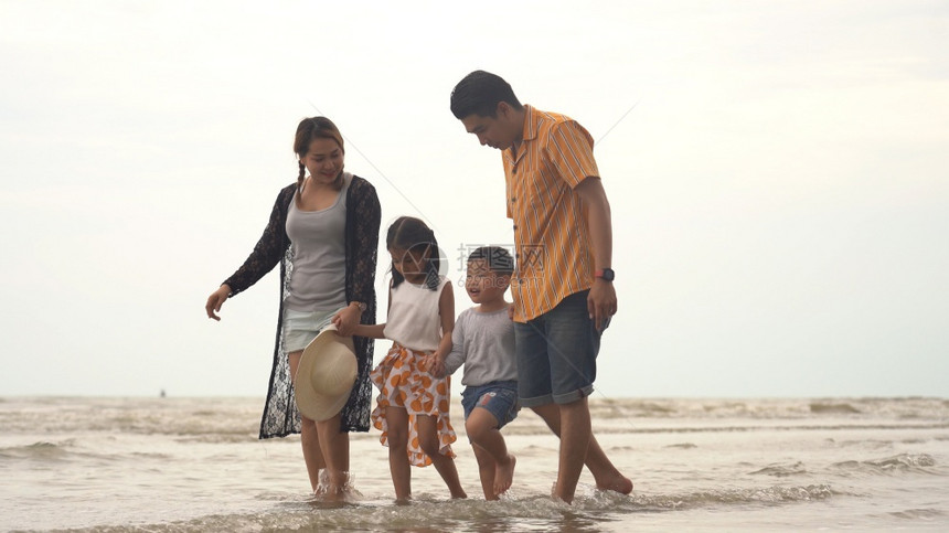 欢乐的亚洲家庭享受在海滩散步图片