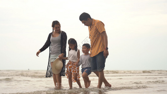 欢乐的亚洲家庭享受在海滩散步图片