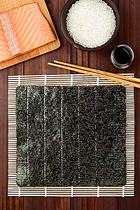 醋溜木须烹饪制造寿司成料诺伊海草在木须竹垫上拍摄滚动新鲜生鲑鱼寿稻大米酱油和筷子边背景