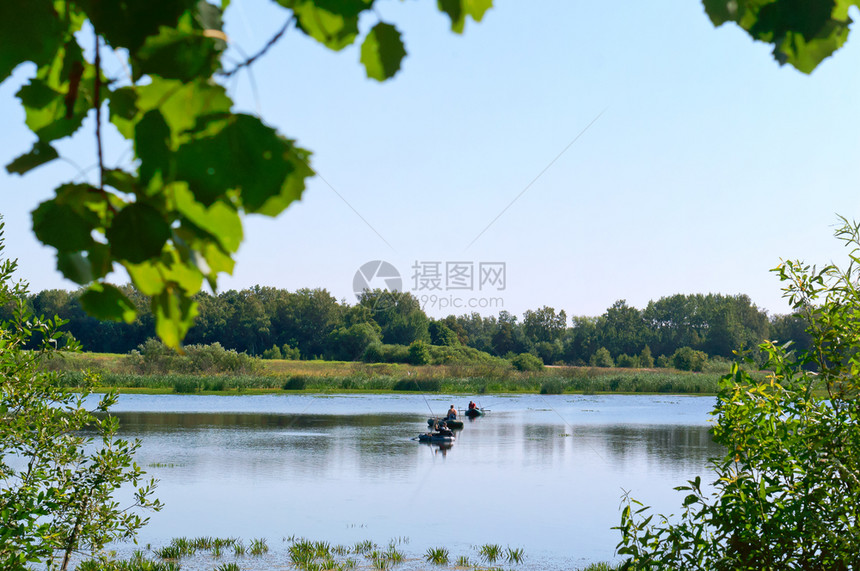 渔夫绿色民在船上三艘湖中森林图片