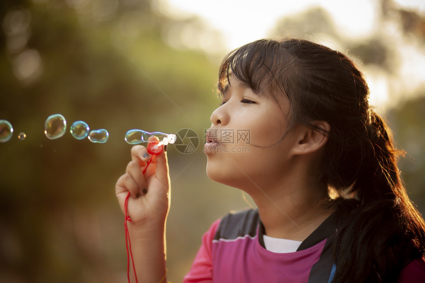 脸气泡女亚裔青少年在与美丽的太阳光相对汤泡中放松图片