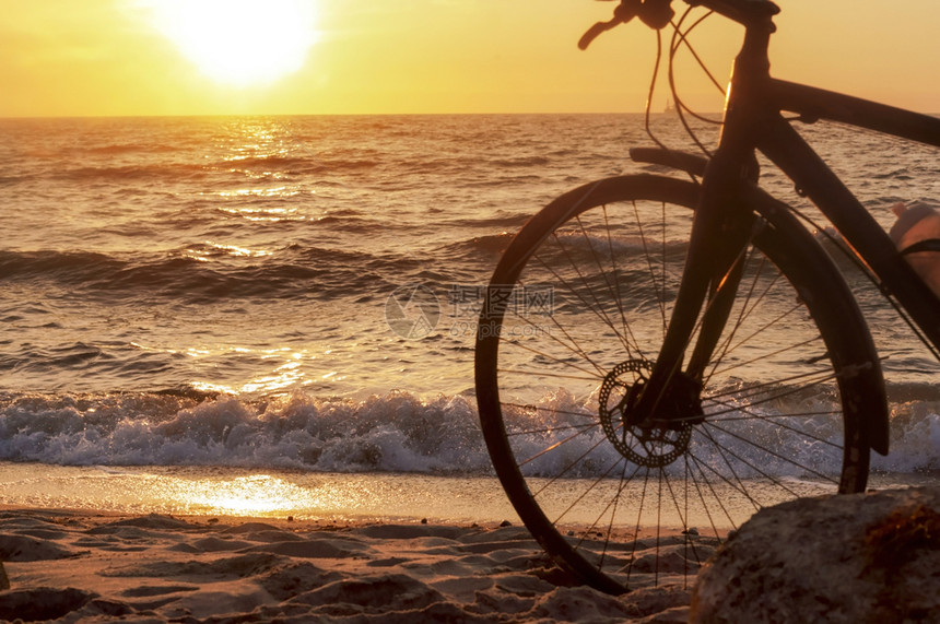 日落时停靠在沙滩上的自行车图片