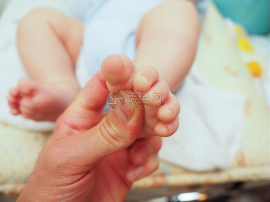 一种婴儿在用拇指换尿布后接受脚按摩看守人接收图片
