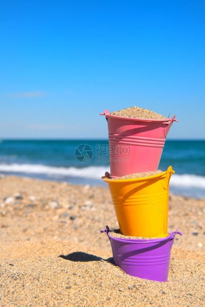 海洋滩上多彩的玩具桶晴天黄色的图片