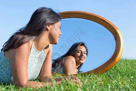 人们镜子面部的女人躺在草地上看着镜像图片