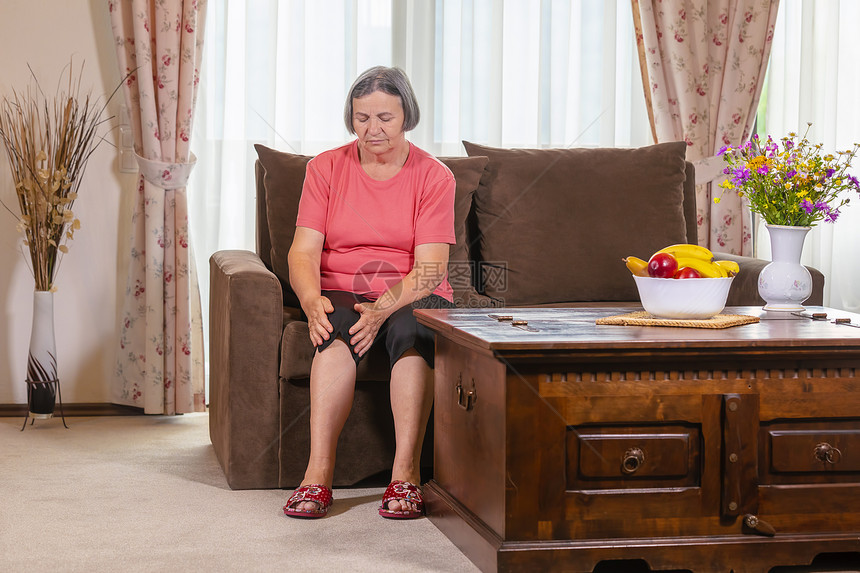 坏的年龄长椅家中膝盖疼痛的老年妇女健康问题与人们对家中腿部疼痛的老年妇女概念图片