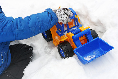 相片模子制作玩冬季游戏的婴儿在雪中玩耍一个儿童坐在白雪上玩具挖土机图片