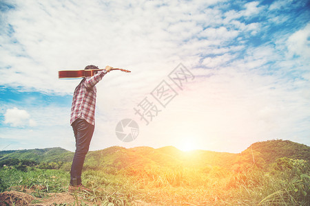 公园人们绿色带着吉他和自然行走的年轻嬉皮士男子RelYounghistster男子拿着吉他与自然行走的在阳光明媚的蓝天在田里放松背景图片