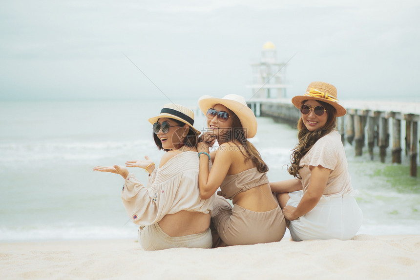 三名亚裔女坐在度假海滨充满幸福的情感中松弛风景优美乐趣图片