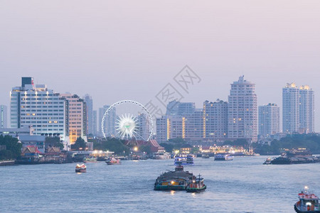 披耶旅行泰国曼谷市晚夜的船河交通日落时建造摩天大楼背景图片