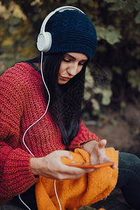 牛仔裤年轻女子在森林里用耳机监听音乐球衣女图片