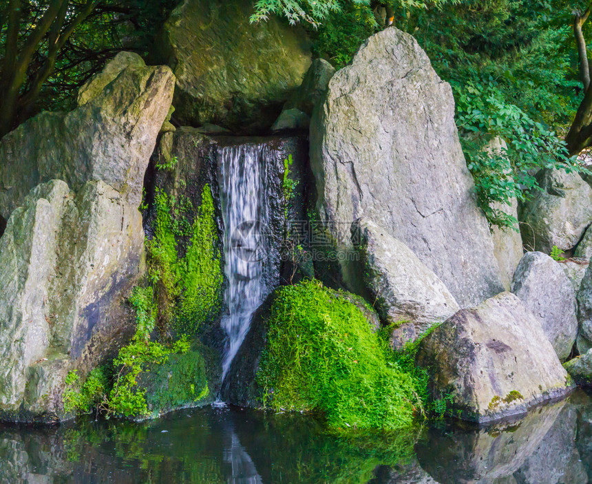 结石美丽的瀑布充满流水大石头和一些被绿苔覆盖的美丽瀑布和平自然风景背绿色场图片