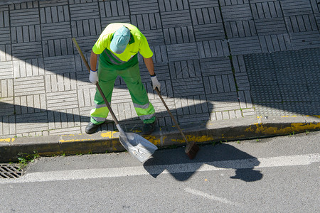 多于扫地工人配有帚和铲子的街道清扫车负责城市公共清洁概念图片