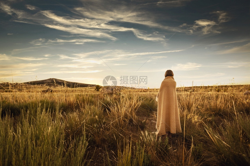日落时女人用黄色的毯子卷起来人们景观温暖的图片