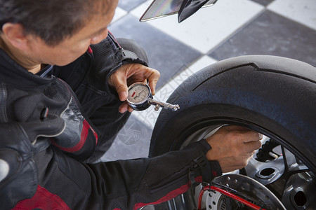 查看大型摩托车后轮的气压检查单机车运动男图片