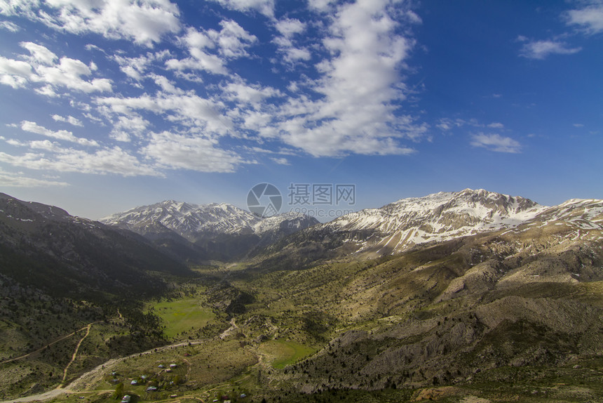 沥青绿色冬天雪地山上一片阴云的天空和高地道路图片