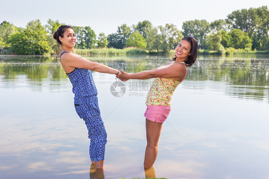 两名女朋友在自然水中共同站在一起天抓住快乐图片