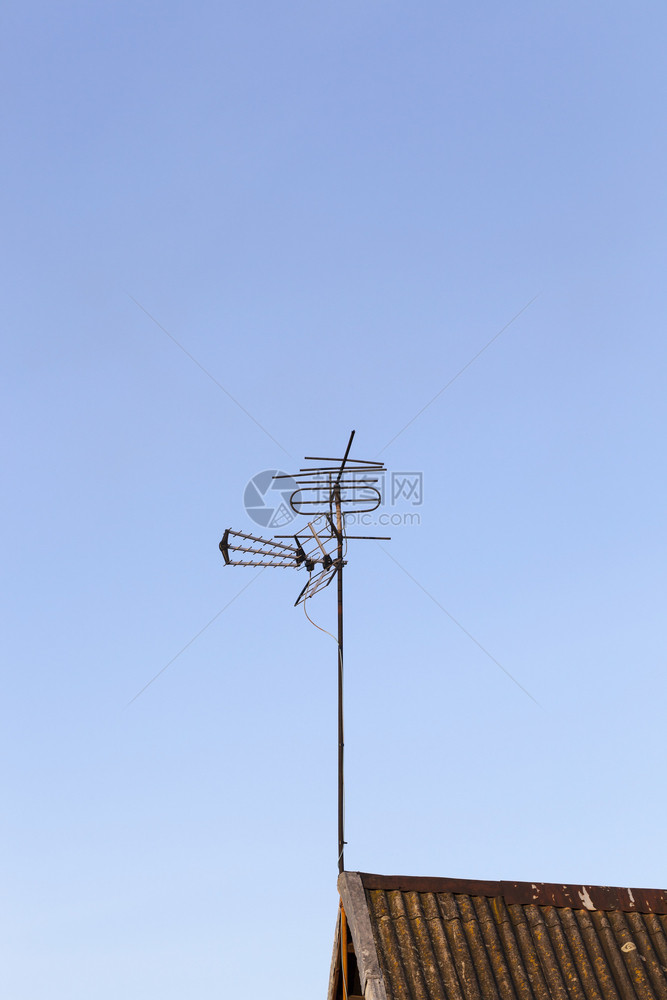 设施用于接收安装在私人住宅屋顶上对蓝天空顶的电视信号金属天线顶渠道私人的图片
