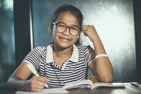 班级身戴眼镜的亚裔青少年在家庭工作时带着堆叠的学校书前台年轻的泰国图片