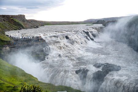 绿色冰岛的瀑布在乌云笼罩的一天流动图片